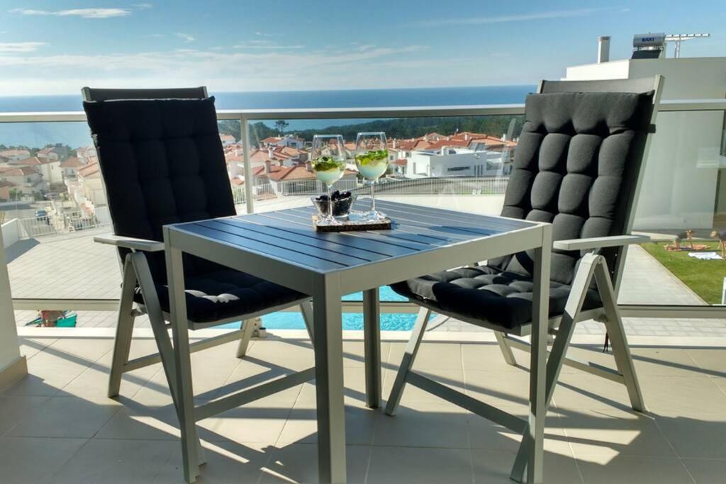einen Tisch und zwei Stühle mit Weingläsern auf dem Balkon in der Unterkunft Gino´s House in Nazaré