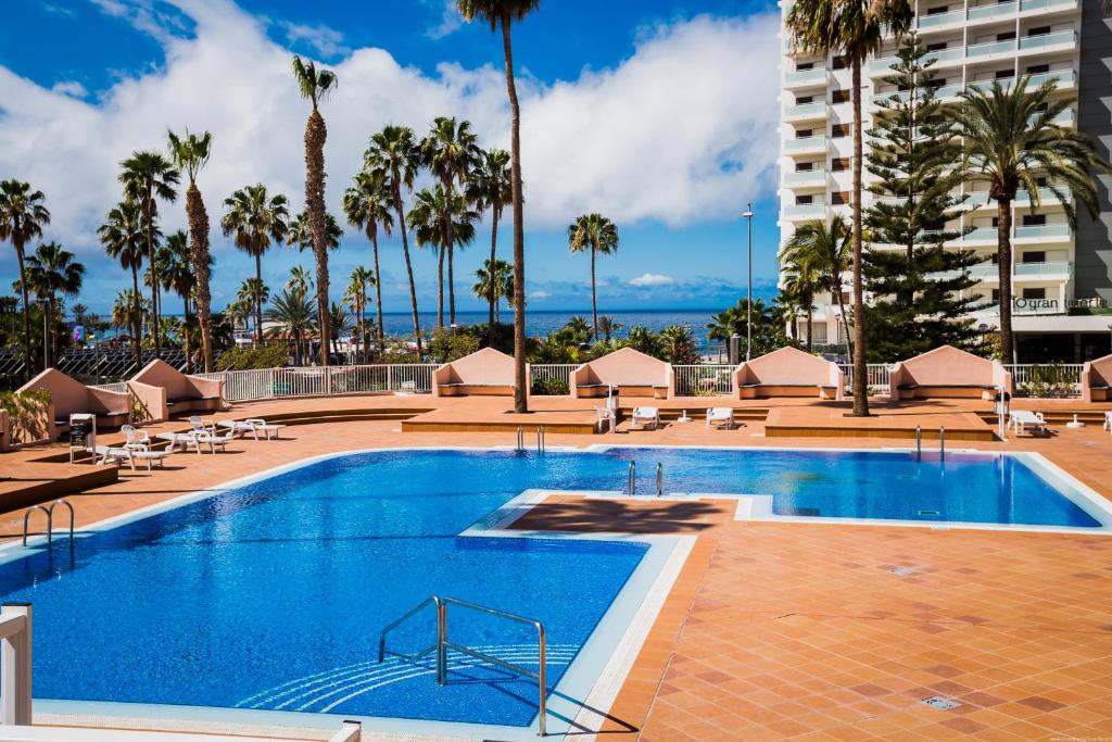 a large swimming pool with palm trees and a building at Las Americas Acapulco Costa Adeje in Playa Fañabe