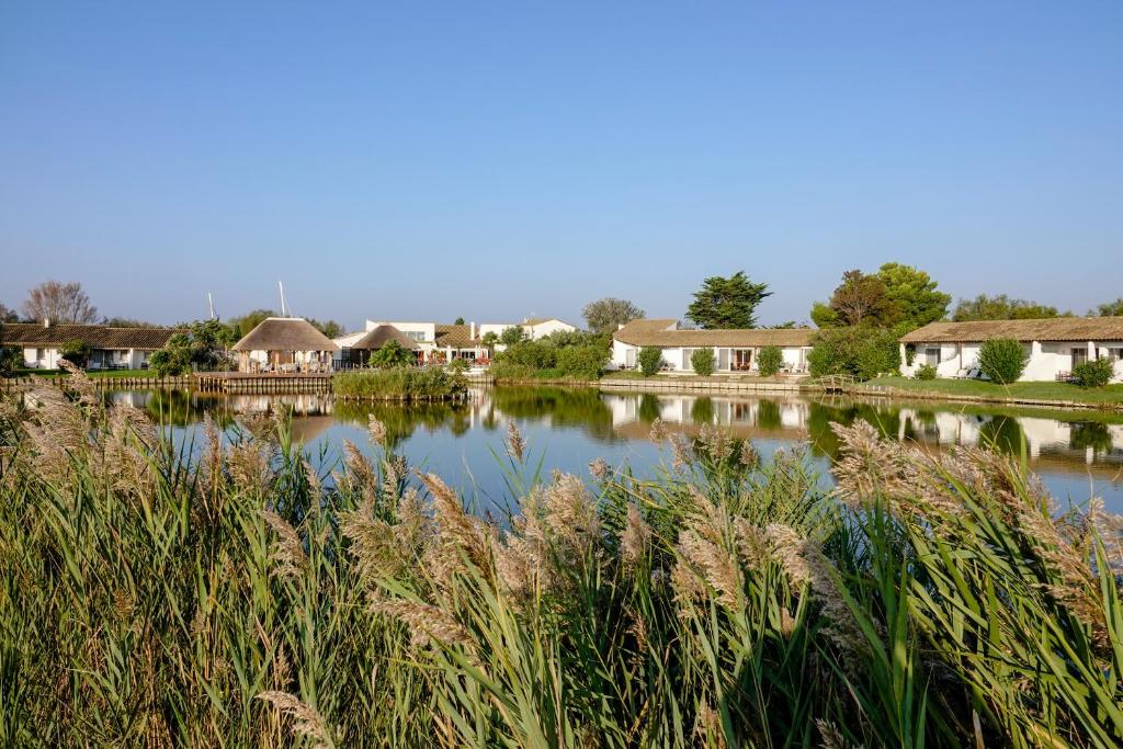 Blick auf einen See mit Häusern und Gras in der Unterkunft Hôtel L' Estelle en Camargue in Saintes-Maries-de-la-Mer