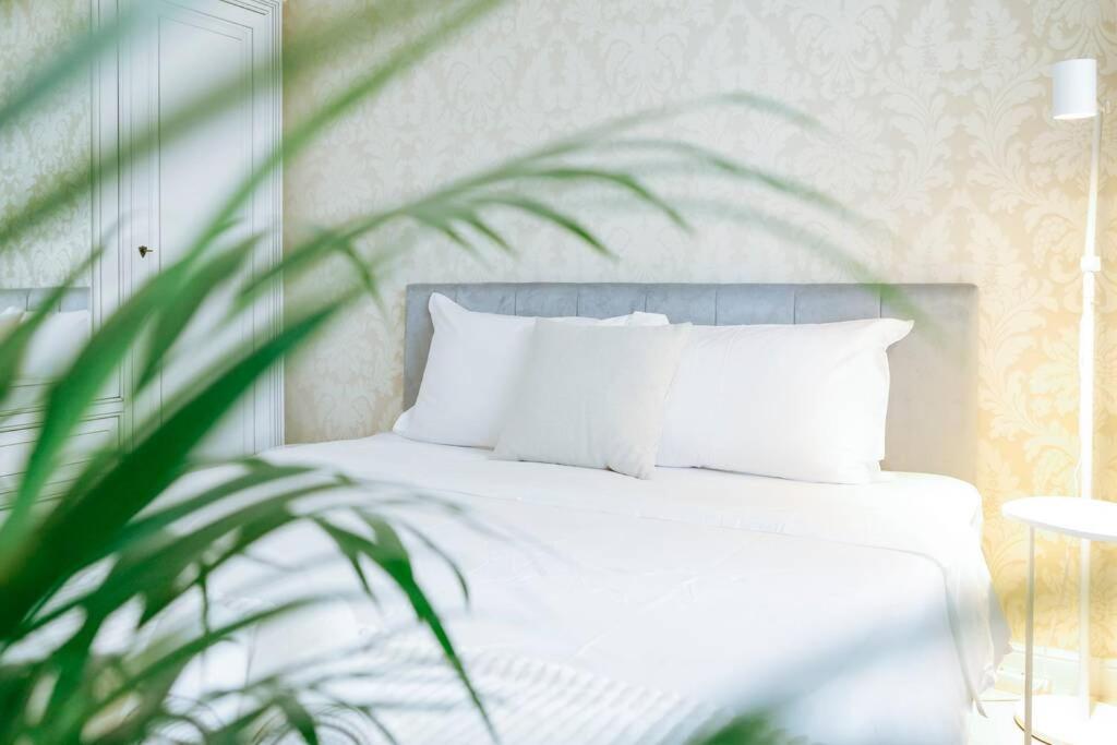 - une chambre avec un lit doté d'oreillers blancs et d'une plante dans l'établissement Elegant Vibes Apartment next to Obor market, à Bucarest