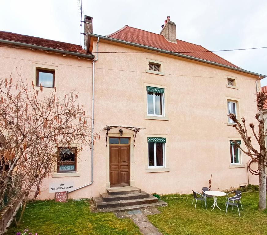 una casa con puerta, mesa y sillas en Les deux Licornes, en Anchenoncourt-et-Chazel