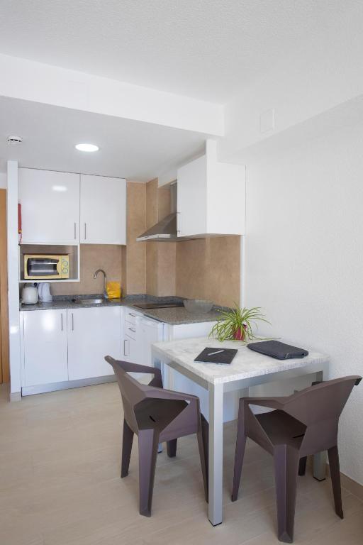 a kitchen with white cabinets and a table and chairs at Aparthotel BCL Levante Club in Benidorm
