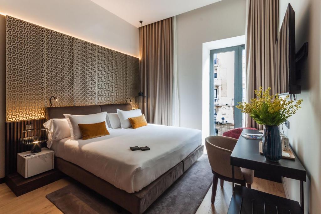 Una habitación de hotel con una cama y un escritorio y un escritorio. en Soho Boutique Catedral, en Sevilla
