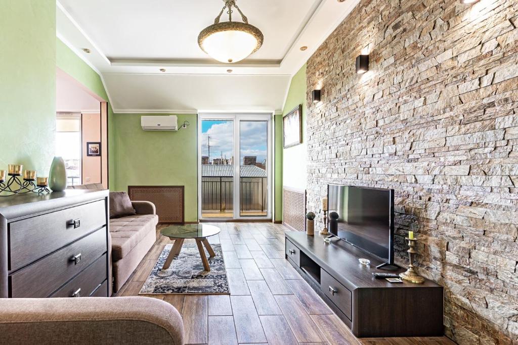 a living room with a tv and a stone wall at Apartments “U prawnika” in Lviv