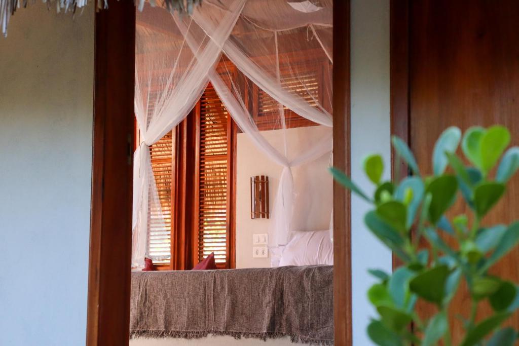 a mirror in a room with a bed and a window at Pousada Iansã in Ponta do Anel