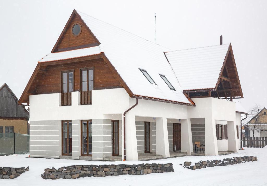 una casa con nieve en el techo en Csató Panzió - Pensiunea Csató en Joseni