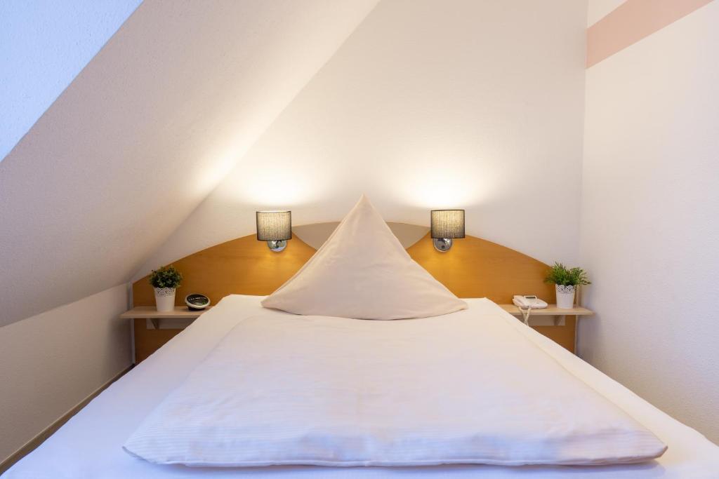 Bett in einem Zimmer mit zwei Lichtern an der Wand in der Unterkunft Hotel Alte Mühle in Chemnitz