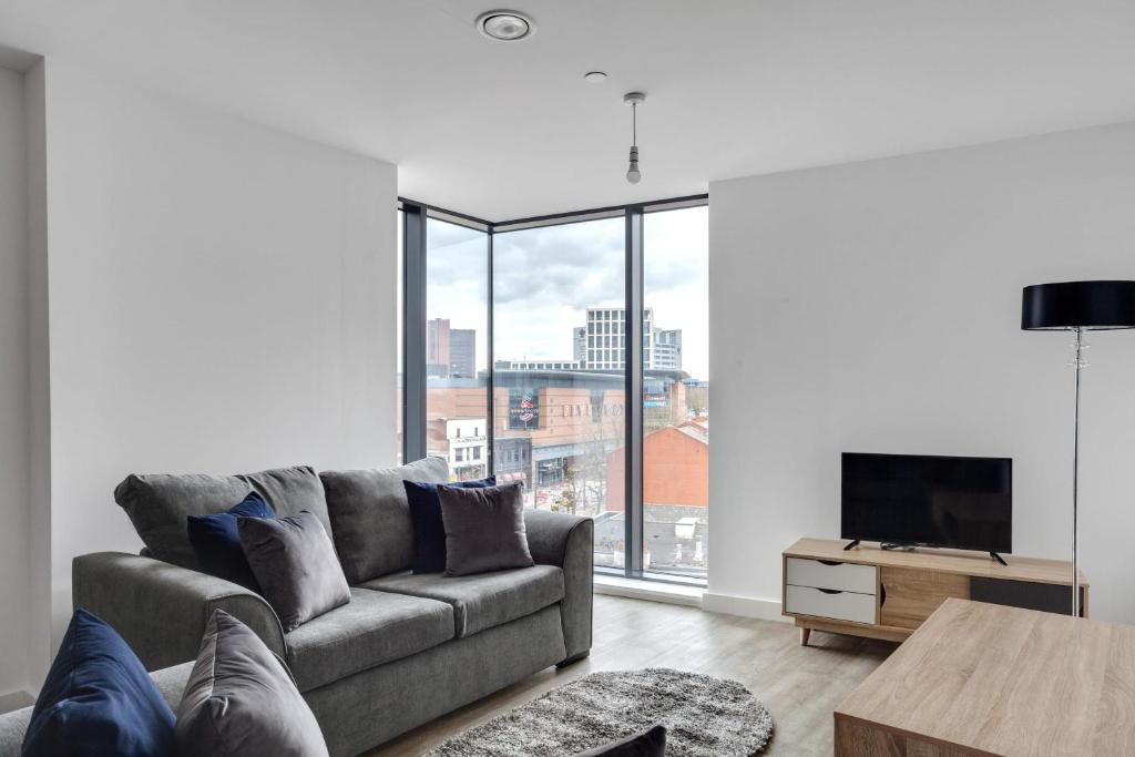 a living room with a couch and a large window at Amazing Apartment in the heart of Birmingham in Birmingham