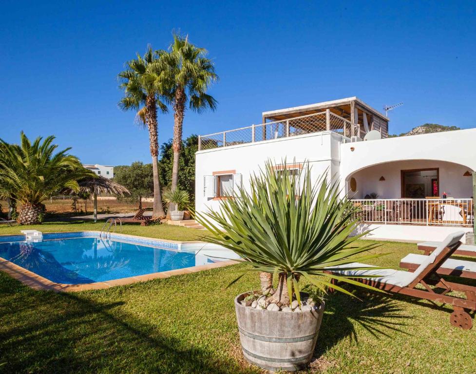 
a large white house with a pool and trees at Villa Es Cubells 204 in Es Cubells
