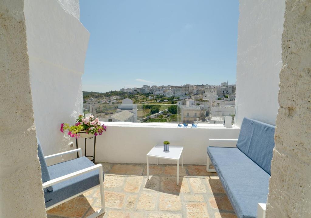 a balcony with two blue chairs and a view of a city at Sunshine Luxury Rooms in Ostuni