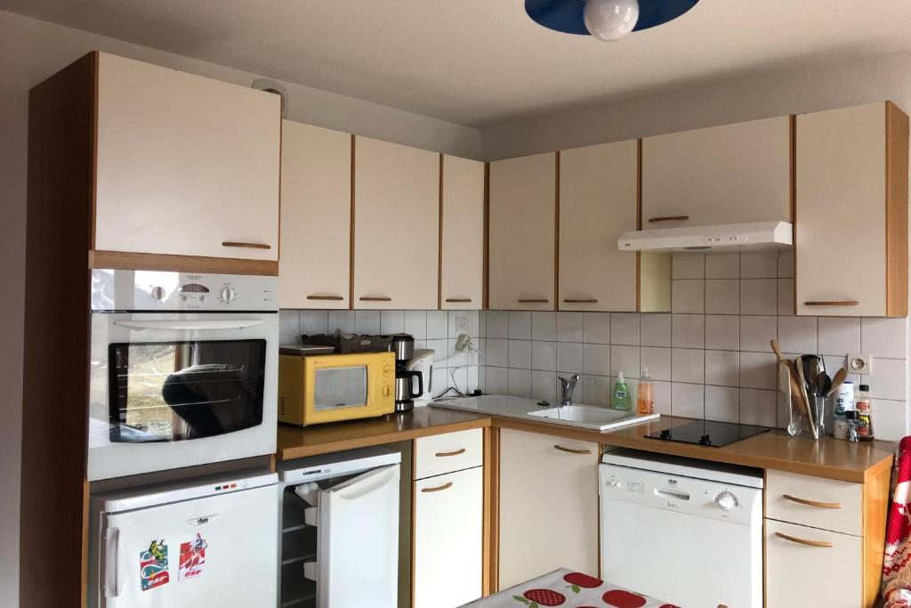 a kitchen with white cabinets and a yellow microwave at The chalet de la Meije - Facing the Plateau d'Emparis in La Grave