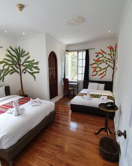 a bedroom with two beds and a table in it at Hotel Boutique Villa de Sant Refugio de Relajacion in Quito