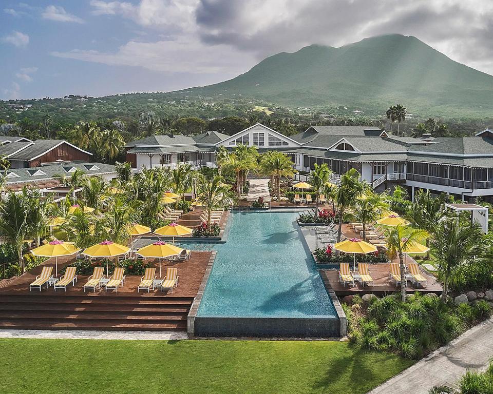 an aerial view of a resort swimming pool with chairs and umbrellas at Four Seasons Resort Nevis in Nevis