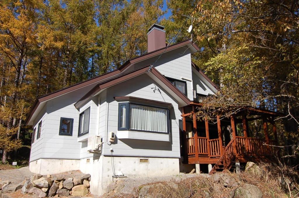 Numanokura的住宿－Shakunagedaira Rental cottage - Vacation STAY 18462v，树林中带门廊的白色小房子