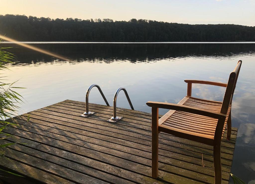 a wooden dock with a chair on a lake at Haus am Pinnower See in Pinnow