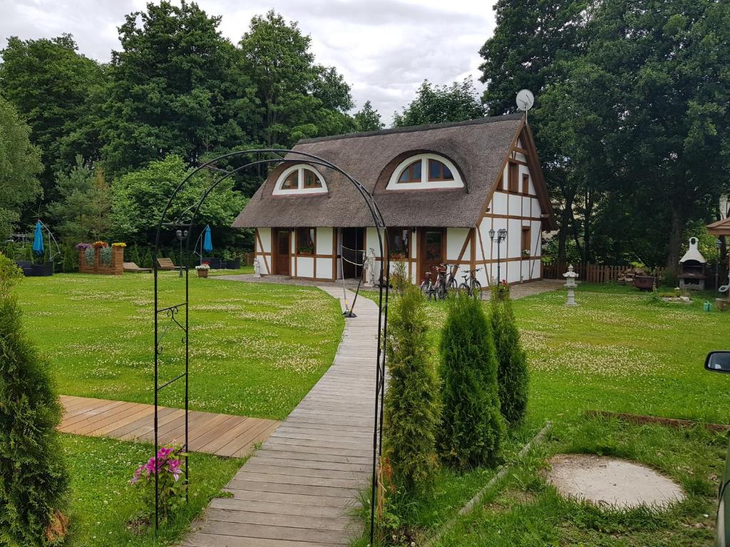 een klein huis in een tuin met een loopbrug bij Chata Pod Strzechą in Lipusz