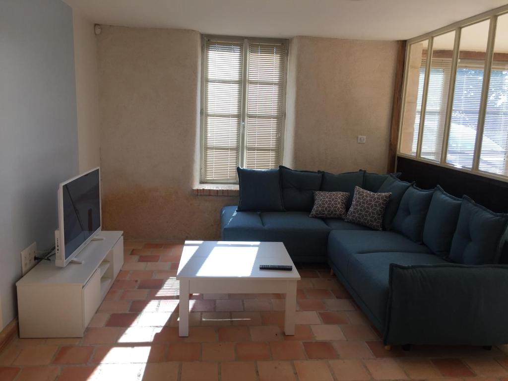 a living room with a blue couch and a tv at Les portes du marais in Benet