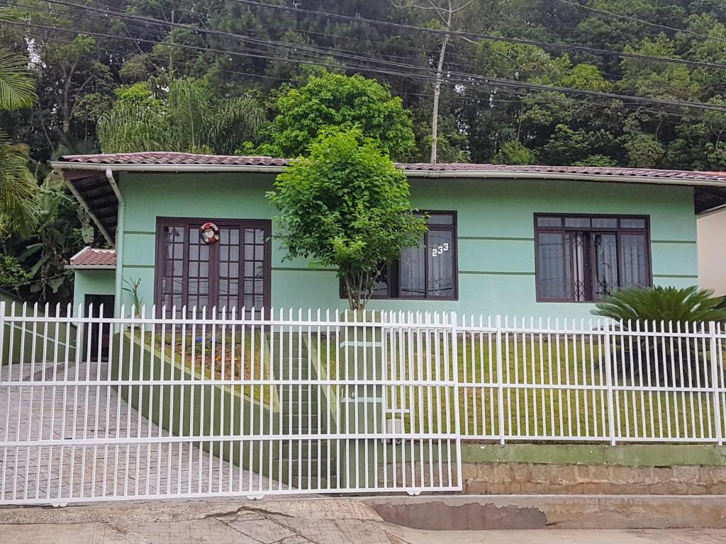 ein kleines grünes Haus mit einem weißen Zaun in der Unterkunft Casa para hospedagem temporário in Joinville