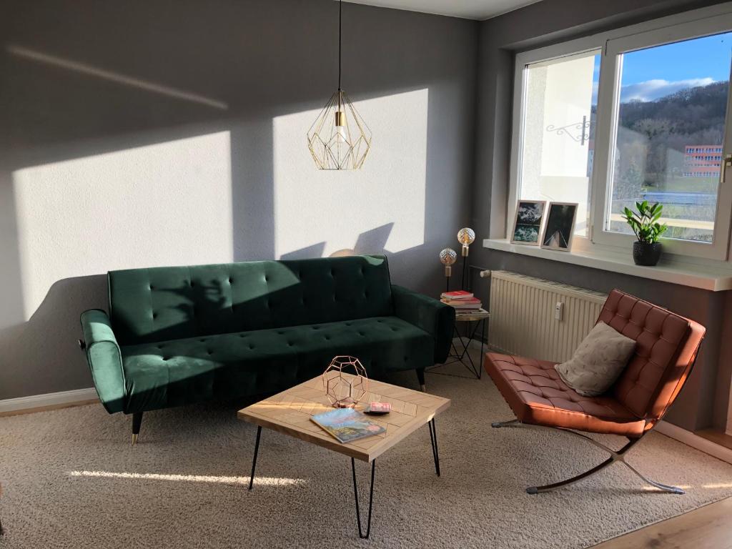 a living room with a green couch and a table at Schwarzburg Appartments in Sondershausen