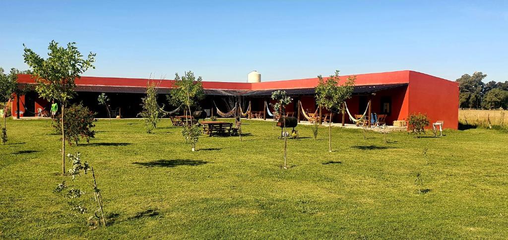 a red building with a table and trees in a field at La Maína Uribe Posada in Uribelarrea