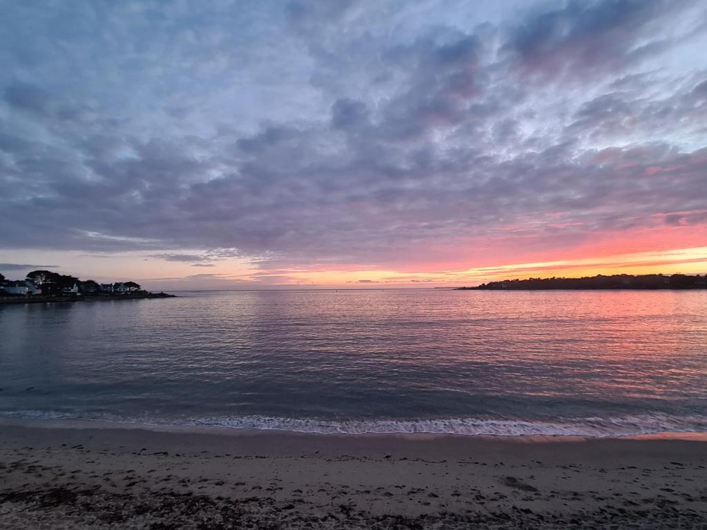 una puesta de sol sobre el agua con una playa en Corniche de la Plage classé 3 étoiles en Bénodet