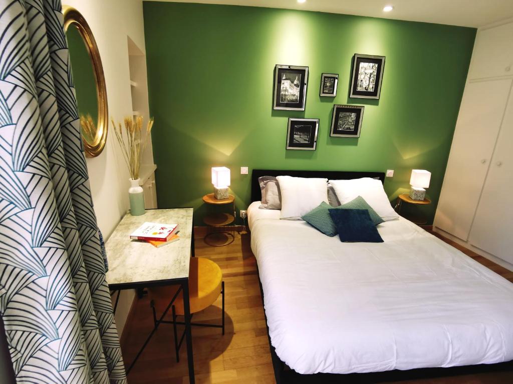 una camera con un letto bianco e una parete verde di Premier Chapitre - Design et charme de l'ancien en cœur de ville a Saint-Brieuc