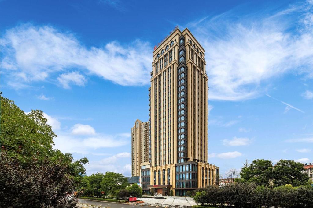 wysoki budynek z zegarem na boku w obiekcie Ramada Plaza by Wyndham Wuhan Huangpi w mieście Wuhan