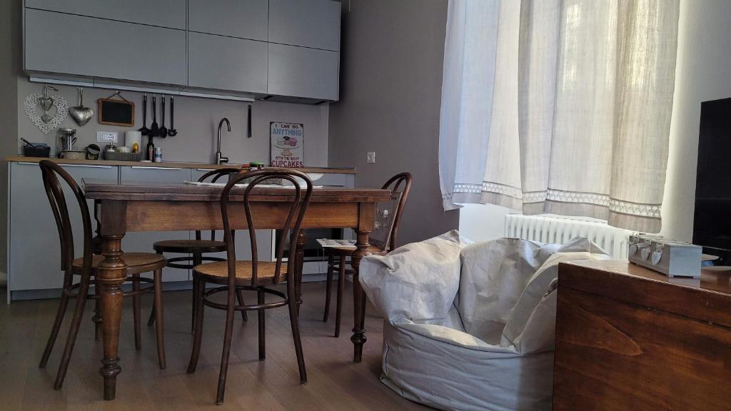 una cocina con mesa de madera y sillas y una cocina con armarios blancos. en Lo Scricciolo, en Rovereto