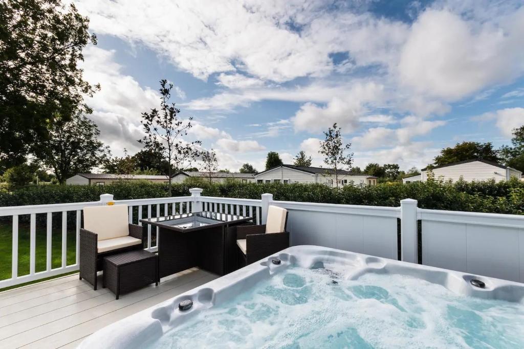 a hot tub on a deck with a table and chairs at The Warren in South Cerney