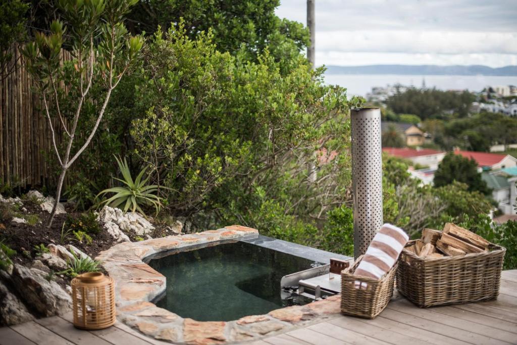 a small pool with a chair and a hot tub on a deck at Ridge House in Hermanus