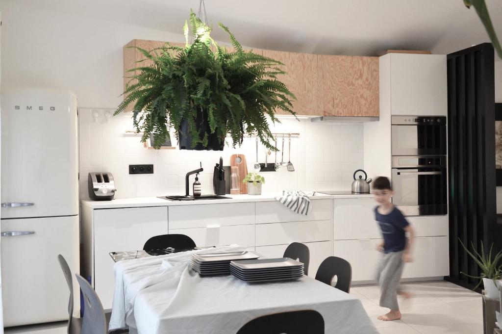 um rapaz de pé numa cozinha com uma mesa em Plaisance Appartements & Suites - Bouguenais Apt em Bouguenais