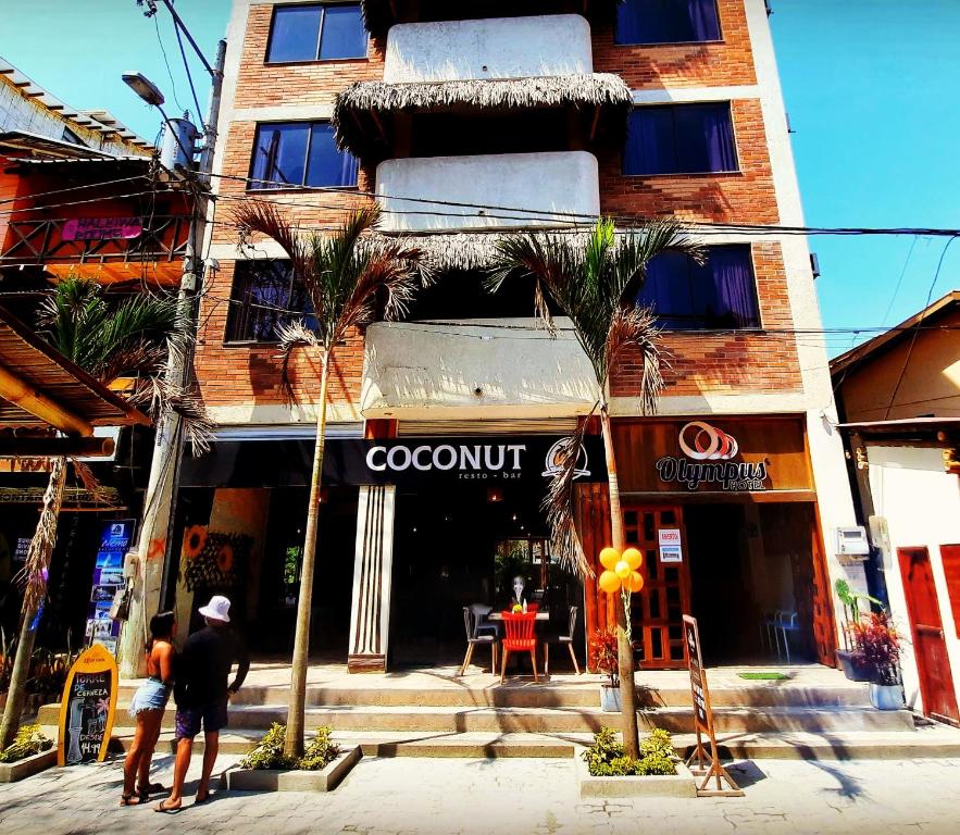 un par de personas de pie en frente de un edificio en Hotel Olympus, en Montañita