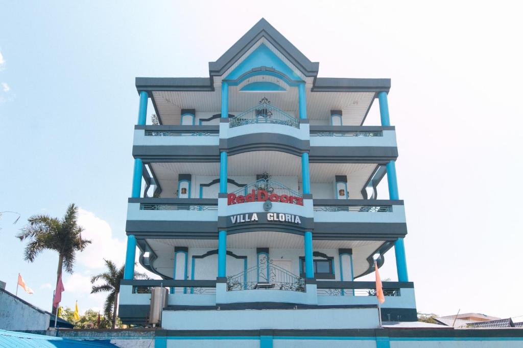 a hotel building with a pool in front of it at RedDoorz Plus Villa Gloria Taguig in Manila