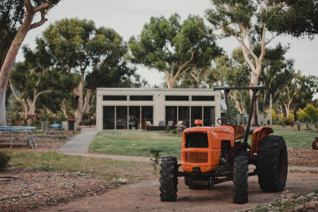 カンガルー・バレーにあるBanksia Park Cottagesの建物前に停車したオレンジ色のトラクター