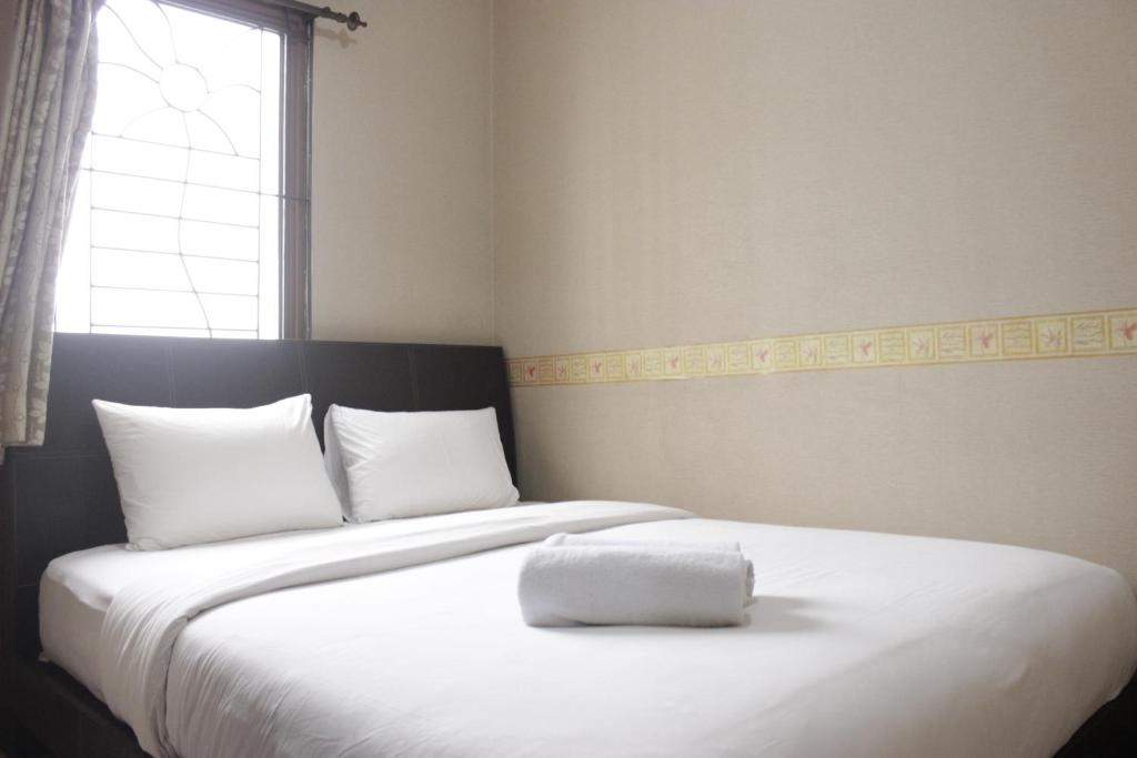 una camera da letto con un grande letto bianco con una finestra di Strategic & Cozy 2BR at Majesty Apartment near Maranatha Christian University By Travelio a Bandung