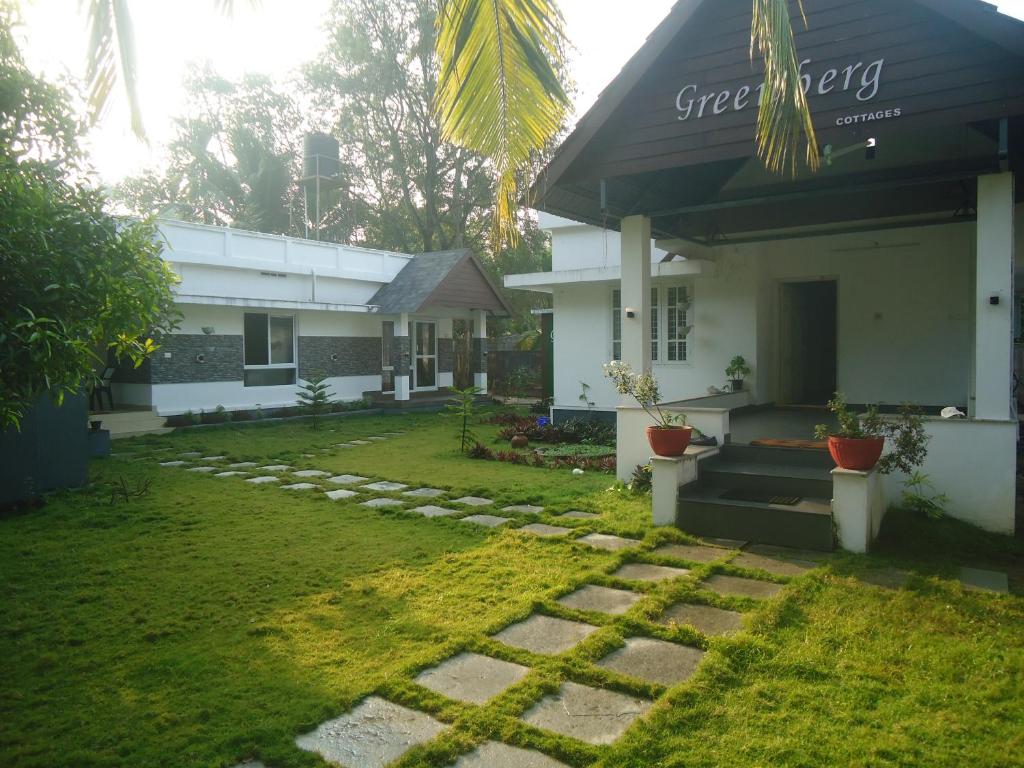 a house with a grass yard and a building at Greenberg cottages Mararikulam in Mararikulam
