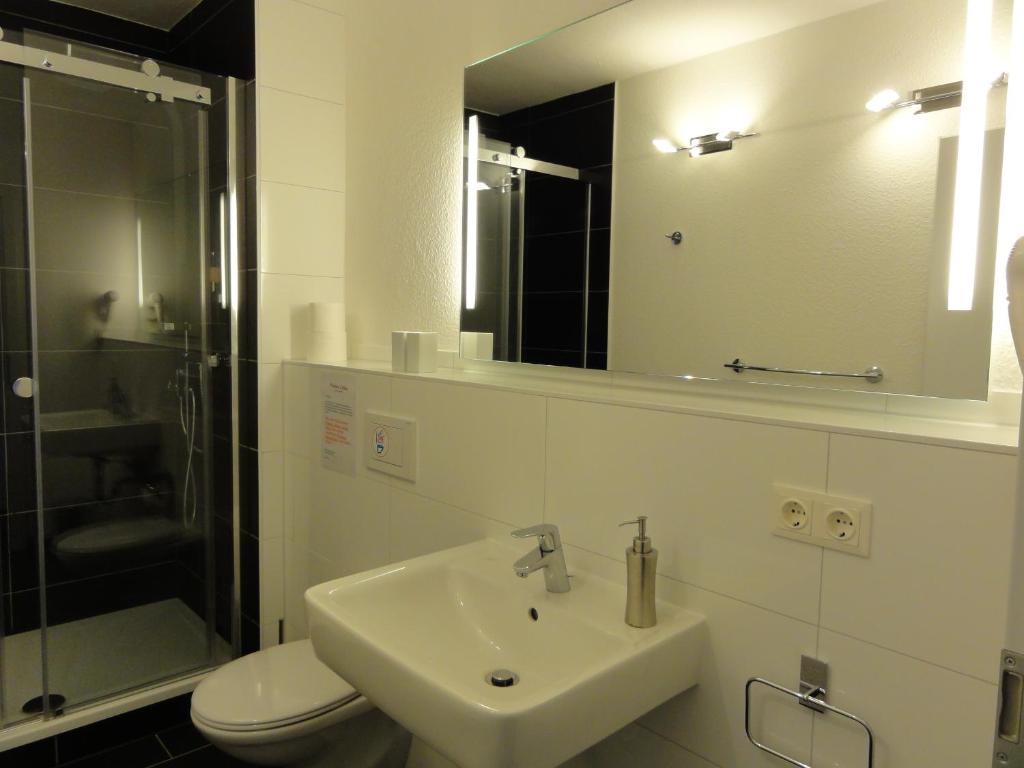 a bathroom with a sink and a toilet and a mirror at Pension Zeitlos in Potsdam