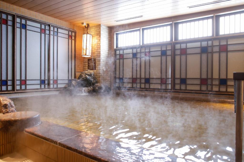 una grande piscina d'acqua in una stanza con finestre di Dormy Inn Kobe Motomachi Natural Hot Springs a Kobe