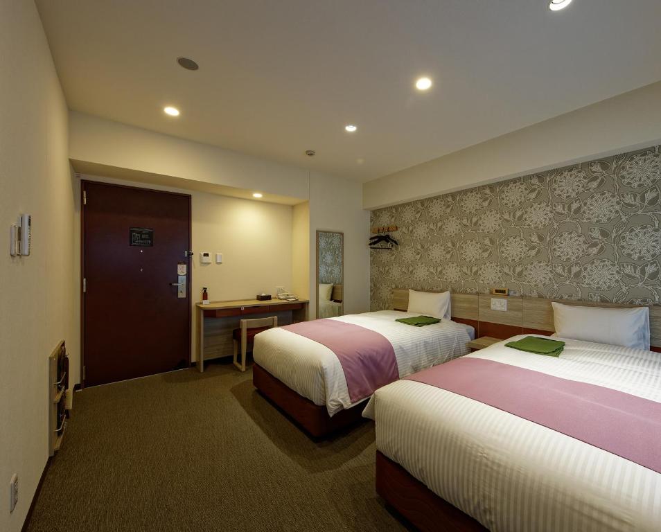 um quarto de hotel com duas camas e uma secretária em Kuretake Inn Premium Meieki minami em Nagoia