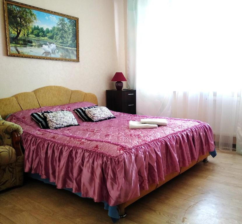 a bedroom with a bed with a pink bedspread at LikeHome Apartments in Velikiy Novgorod