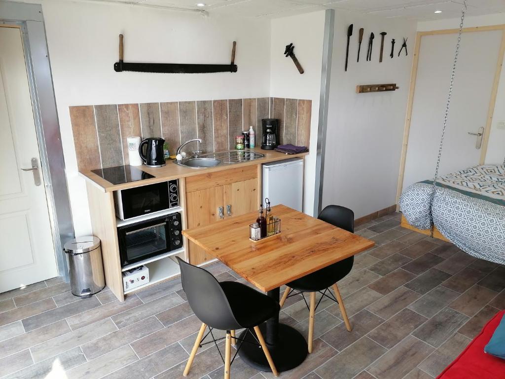 a kitchen with a wooden table and chairs in a room at Best Price #2 "L'ATELIER" x5 people in Orchamps-Vennes