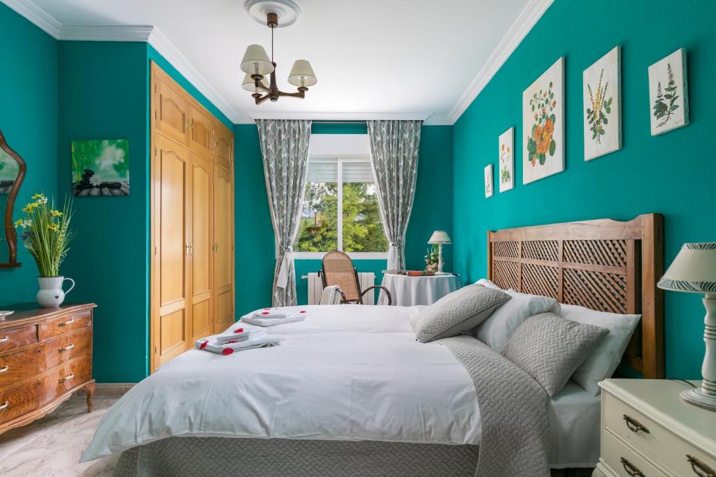 a blue bedroom with a bed and a table at El Jardín de Alameda in Alameda del Valle