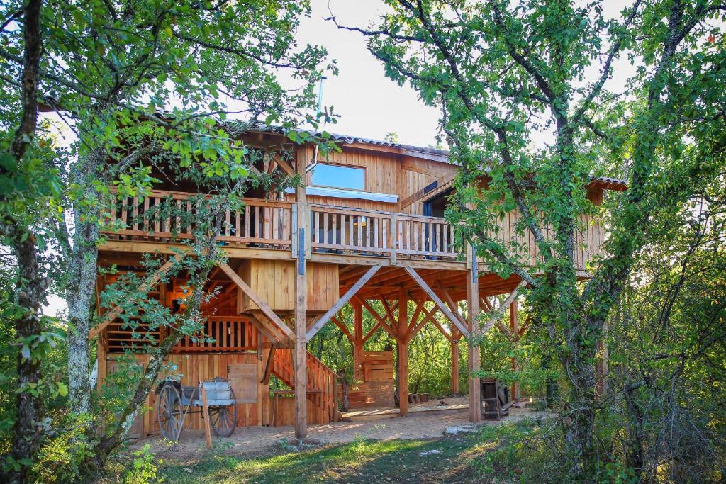 a cabin in the woods with a wrap around deck at La Canopee in Cahuzac-sur-Vère