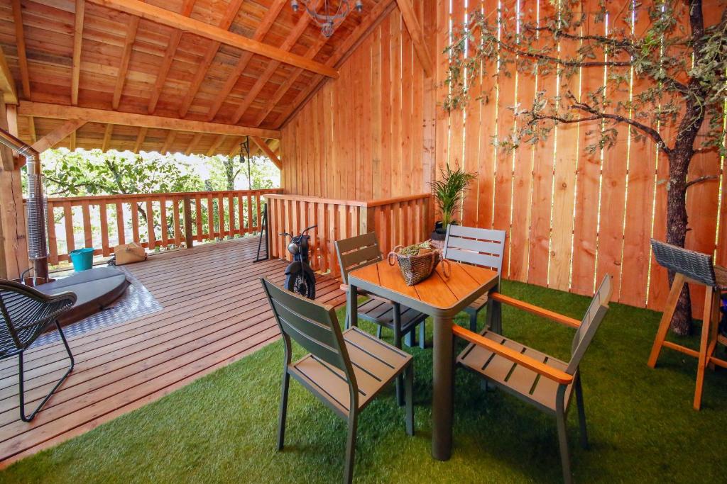 una terrazza in legno con tavolo e sedie. di La Canopee a Cahuzac-sur-Vère