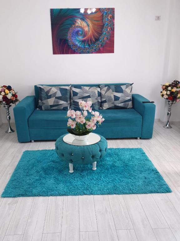 a living room with a blue couch and a table with flowers at Apartament 2 camere Militari Residence new in Roşu