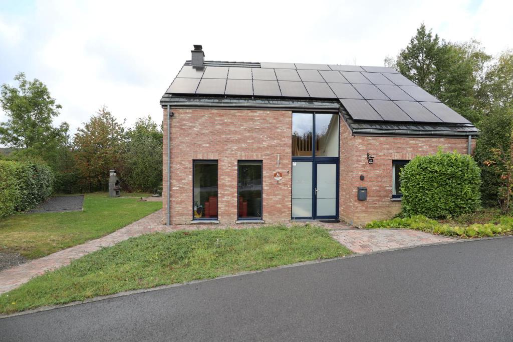 a brick house with a solar roof on a street at Maison Violette in Durbuy