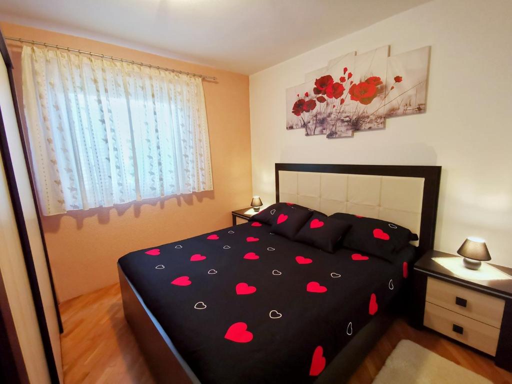 ein Schlafzimmer mit einem schwarzen Bett mit roten Herzen darauf in der Unterkunft Apartman Matej in Tar