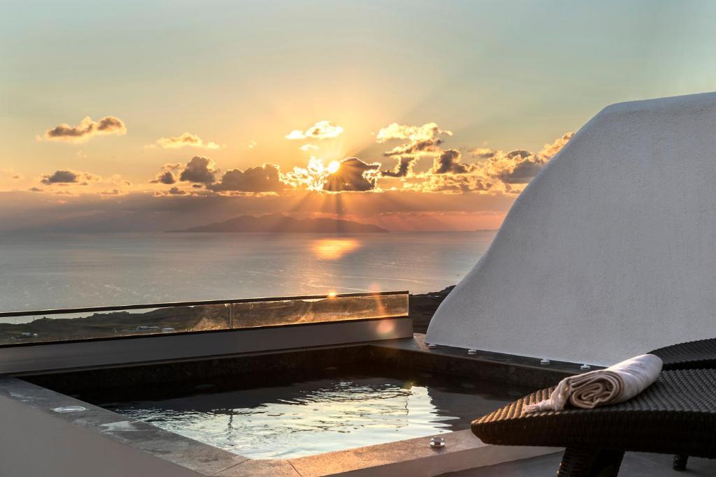 La Estrella 4 Suites with Sea View & 4 Prive Hot Tub في Vourvoúlos: حوض استحمام ساخن مع إطلالة على المحيط عند غروب الشمس