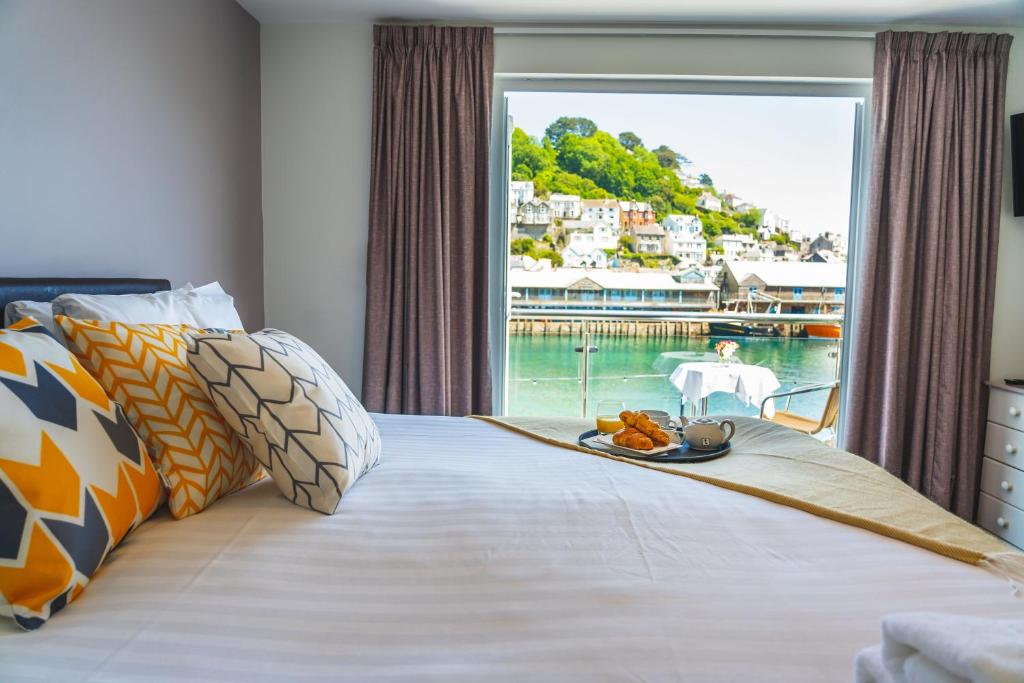 een bed met een dienblad met eten en een raam bij Portbyhan Hotel in Looe