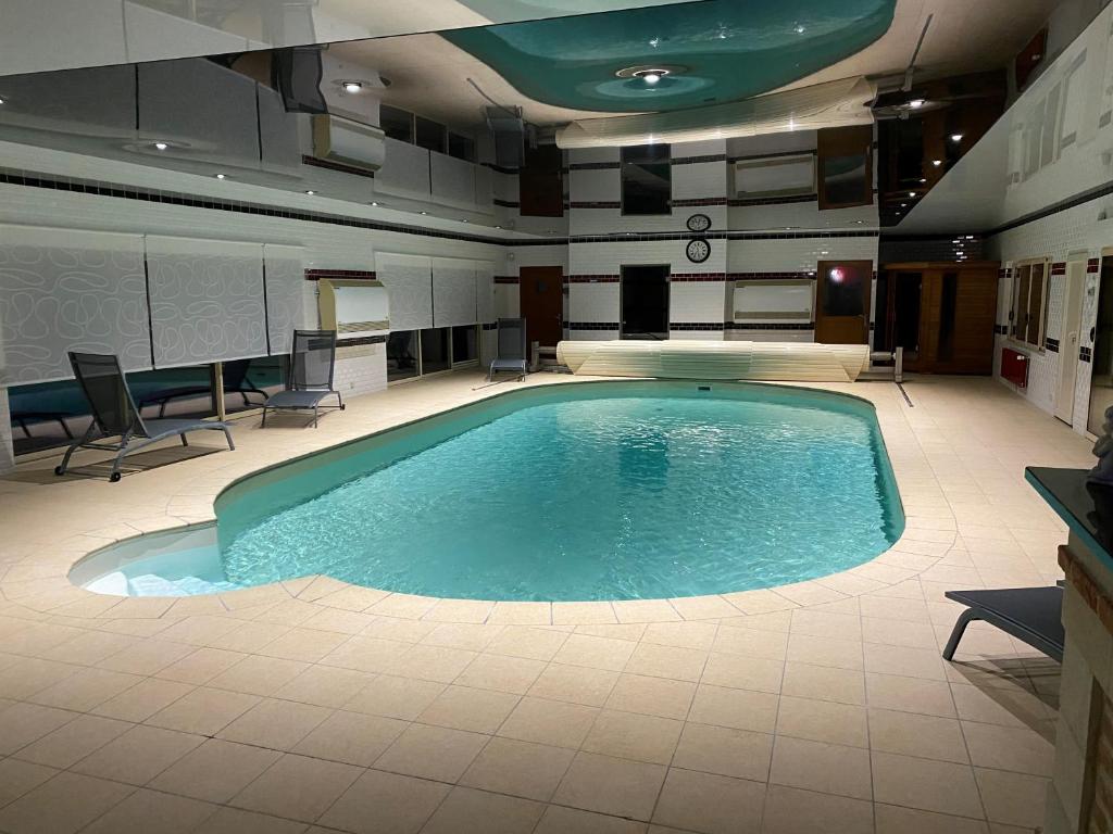- une grande piscine dans une pièce avec des chaises et des tables dans l'établissement Domaine du Clos Pallacien, à Paillé